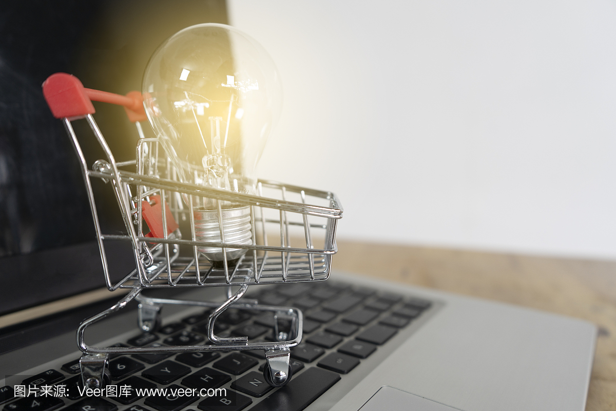 笔记本电脑键盘上的手推车上的灯泡。网上购物是一种电子商务形式,它允许消费者通过互联网直接从卖家那里购买商品。